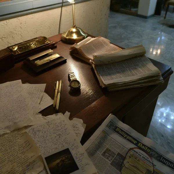A study desk covered in aged documents and artifacts